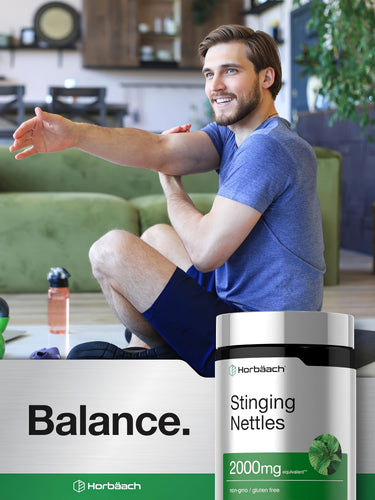 View 6 Young man smiling while stretching his arm, with a Horbäach Stinging Nettles bottle prominently in the foreground.