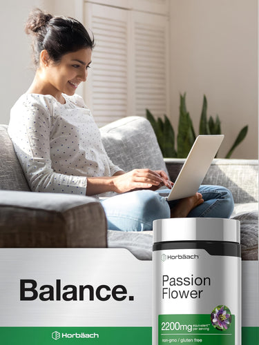 View 6 Young adult woman using a laptop on a couch with a Horbäach Passion Flower bottle and the word 'Balance' displayed.