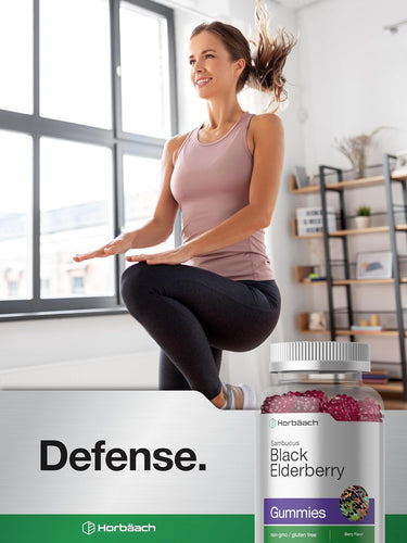 Woman sitting on a table in a bright room with a jar of gummies in front of her.