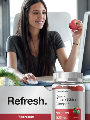 Woman holding an apple with a bottle of Horbaach Organic Apple Cider Vinegar Gummies on a desk.