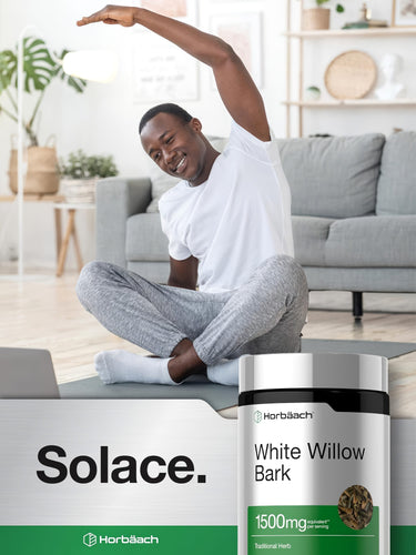View 6 A young adult male stretches on a yoga mat and smiles, next to a bottle of Horbaach White Willow Bark.