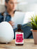 Bottle of Plumeria fragrance oil next to a diffuser on a table with a blurred person in the background.