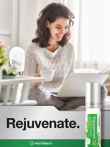 Woman using a laptop with a bottle of Peppermint Oil and a box labeled 'Rejuvenate' in the foreground.