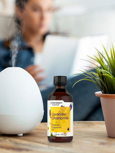Bottle of lavender chamomile fragrance oil on a table with a diffuser and plant in the background.