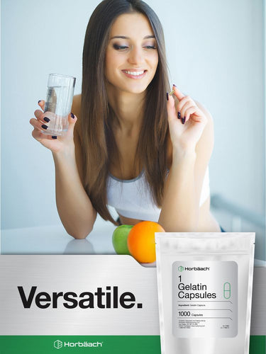 Woman holding a glass of water with gelatin capsules and oranges in the background.