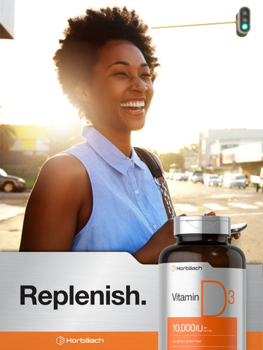 View 6 Woman smiling at a crosswalk with a bottle of vitamin D3 in the foreground.