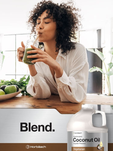 Person drinking a green smoothie with a jar of coconut oil blend in the foreground.