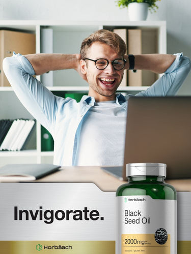 Man relaxing in office with bottle of black seed oil in foreground.