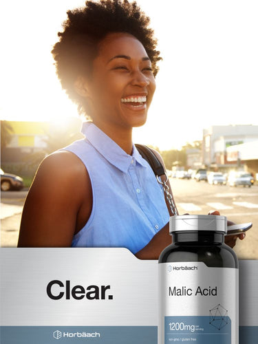 Woman smiling outdoors with a bottle of malic acid supplement in the foreground.