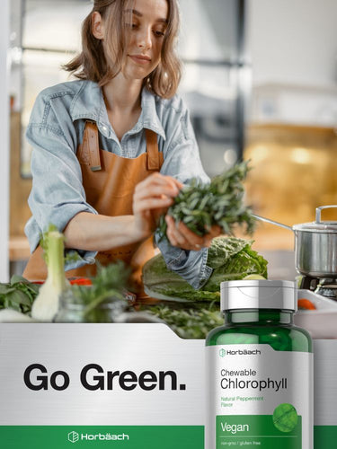 View 6 Woman in a kitchen with a bottle of Herb Bach Chewable Chlorophyll supplement.