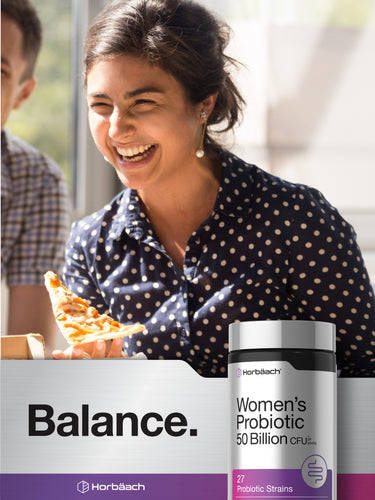 View 6 Young woman laughs while holding a pizza slice and a Women's Probiotic bottle.