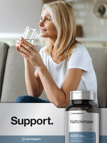 View 6 Woman holding a glass of water with a bottle of Nattokinase in the foreground.