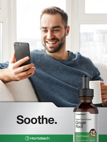 Man using a smartphone with a bottle of ginger root extract in the foreground.