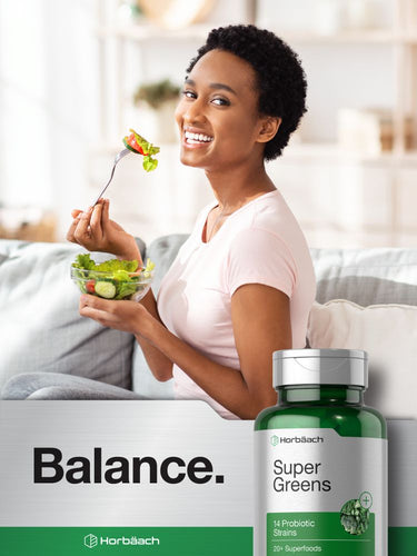 View 6 Woman holding a salad with a bottle of Herbäuch Super Greens on a white background