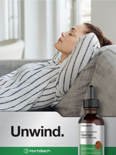 View 6 Woman relaxing on a couch with a bottle of Horbaach Valerian liquid extract labeled 'Unwind'.