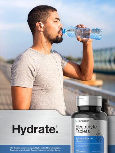 View 6 Man drinking water with electrolyte tablet bottle in foreground