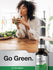 Woman drinking green juice with a bottle of Horbaach Liquid Chlorophyll on a kitchen counter.