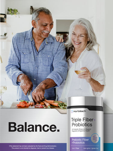 View 6 Older couple laughing and preparing food in a kitchen with a bottle of Horbäach Triple Fiber + Probiotics on the counter.