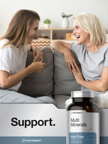 View 6 Two women sitting on a couch with a bottle of Harbäsch Multi Minerals Iron Free supplement in the foreground.