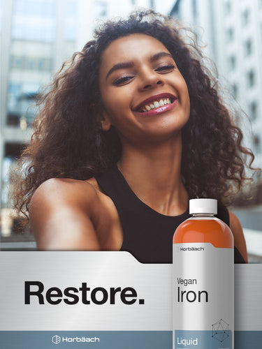 View 6 Woman with a bottle of Harbäch Vegan Iron Liquid against a blurred cityscape background