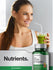 Woman holding a green smoothie with a bottle of supplements labeled 'Mega Fruits & Veggies'.