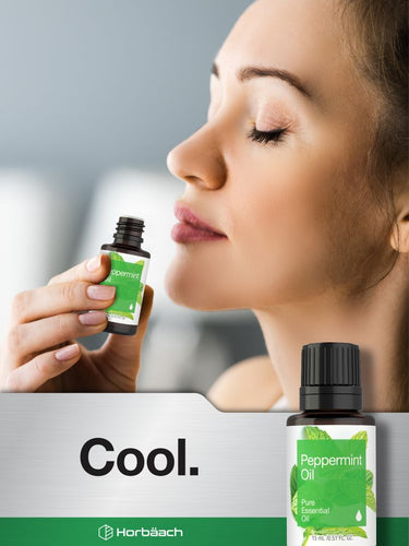 Person applying peppermint oil near their nose with product packaging visible.