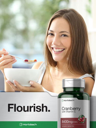 Woman enjoying a healthy snack with a bottle of Cranberry with Vitamin C supplement in the foreground.