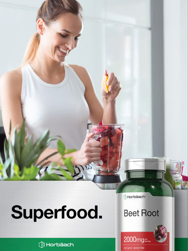 View 7 Young adult woman making a smoothie, adding lemon to a blender with beet pieces, beside a Horbäach Beet Root bottle.