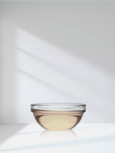 View 7 Glass bowl with liquid on a reflective surface against a white background