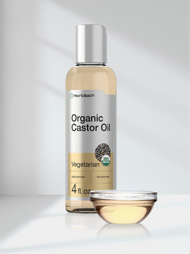 Bottle of Organic Castor Oil with a dropper on a light gray background