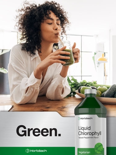 View 7 Person drinking green juice with a bottle of liquid chlorophyll in the foreground.