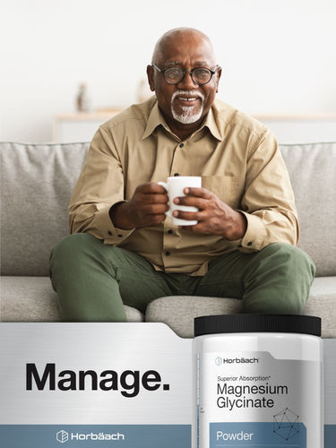 View 7 Man sitting on a couch holding a mug with a product container for magnesium glycinate powder in the foreground.