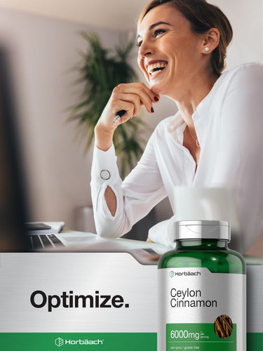 Woman smiling at a desk with a bottle of Ceylon Cinnamon in front of her.