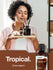view 7 Woman holding a tray with coconut-scented products and a bottle of Horbaach Coconut fragrance on a brown background.