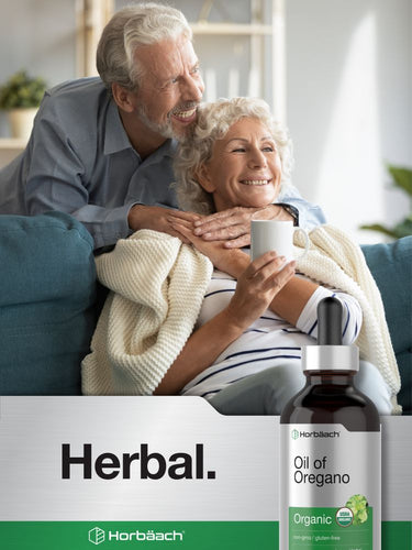 Senior couple smiling at home with a bottle of oil of oregano in the foreground.