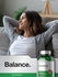 Woman relaxing on a couch with a bottle of Pine Bark supplement in the foreground.