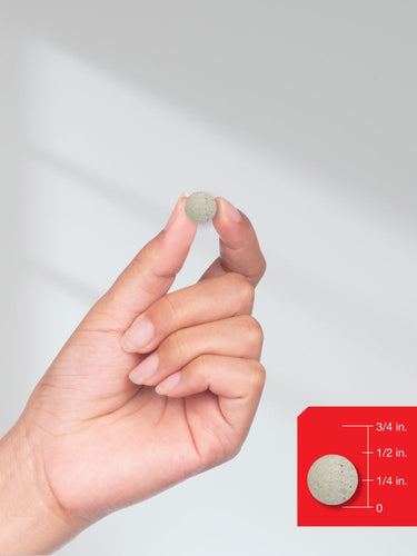 Hand holding a small round object with a size reference on a white background