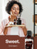 Woman holding a wooden tray with fragrance bottles and a bottle of chocolate fragrance on a brown background.