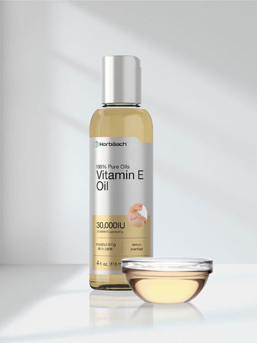 View 7 Bottle of vitamin E oil with a small bowl of the oil on a reflective surface.