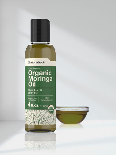 View 7 Bottle of Horbaach Organic Moringa Oil with a small bowl of oil on a light gray background