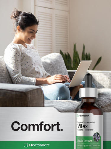 View 7 Woman using a laptop on a couch with a bottle of Vitex liquid extract in the foreground.