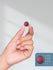 Hand holding a small purple object with a size measurement inset.