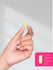 view 8 Hand holding a small yellow pill with a scale next to it on a white background.