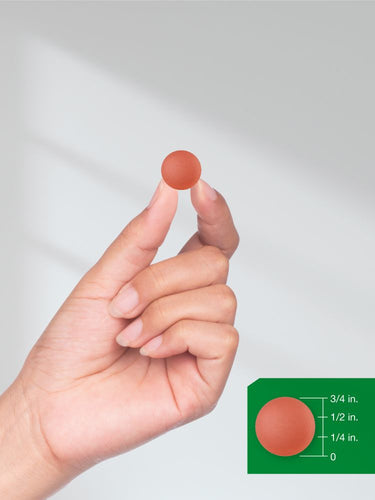 View 8 Hand holding a small red object with a size reference on a green background.