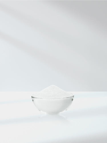Clear glass bowl filled with white powder on a white background