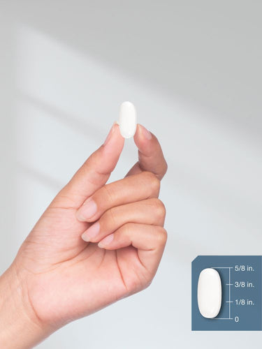 View 8 Hand holding a white pill with a measurement inset on a light gray background