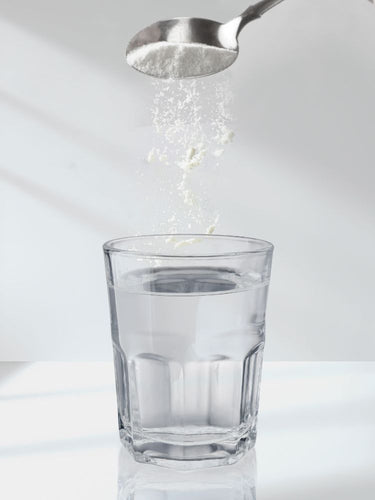 Spoon adding salt to a glass of water on a white background