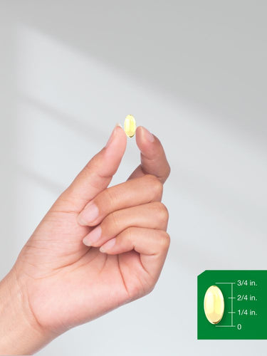Hand holding a pill with a size reference on a gray background