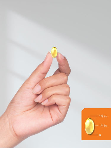 Hand holding a yellow supplement capsule with size comparison on an orange label against a light gray background