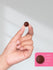 view 8 Hand holding a small brown chocolate against a plain background.
